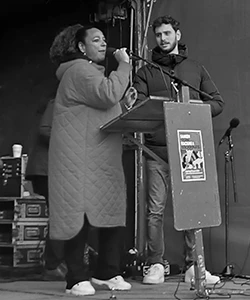 Vrouw spreekt op podium naast man