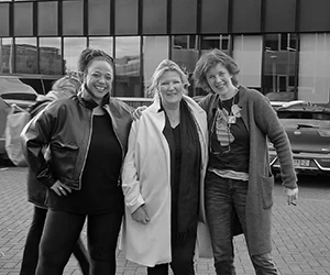 Drie vrouwen lachen samen voor modern gebouw