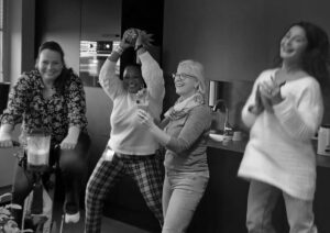 Vier lachende mensen in een keukenomgeving.