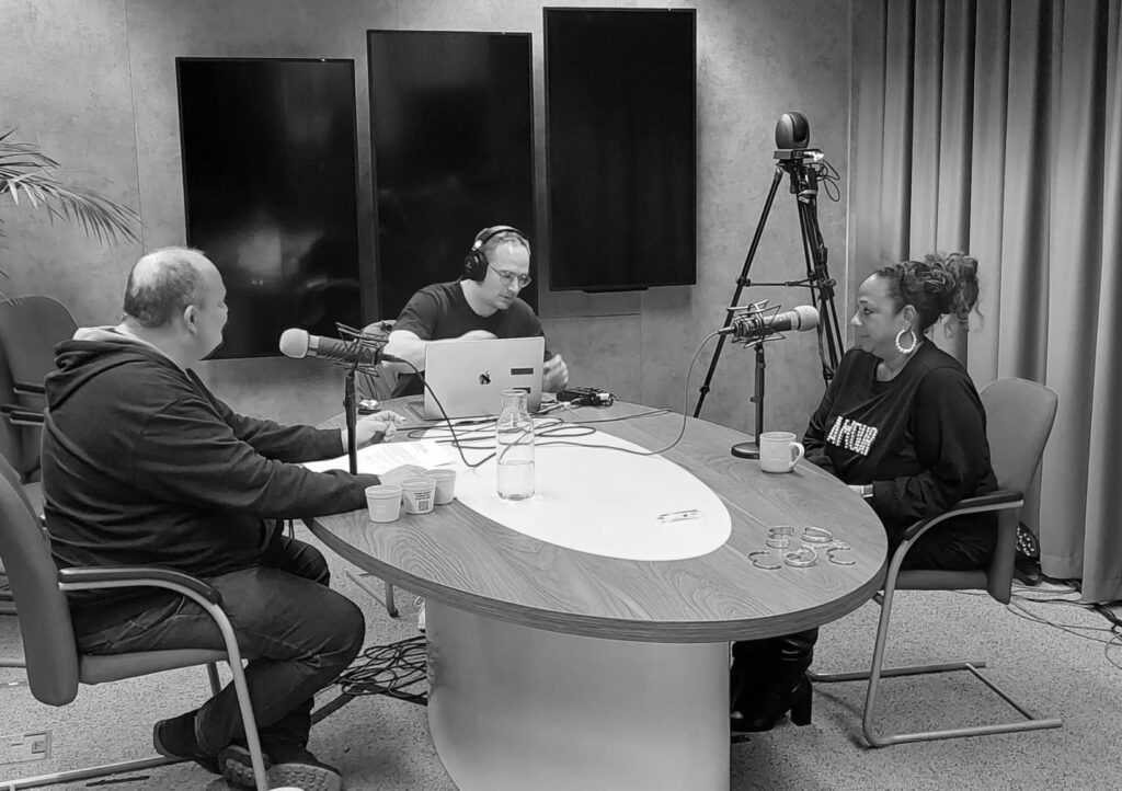 Drie personen nemen podcast op in studio.